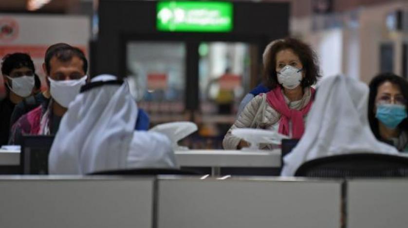 مسافرون يرتدون كمامة واقية أثناء مغادرتهم مطار دبي الدولي (أ.ف.ب)