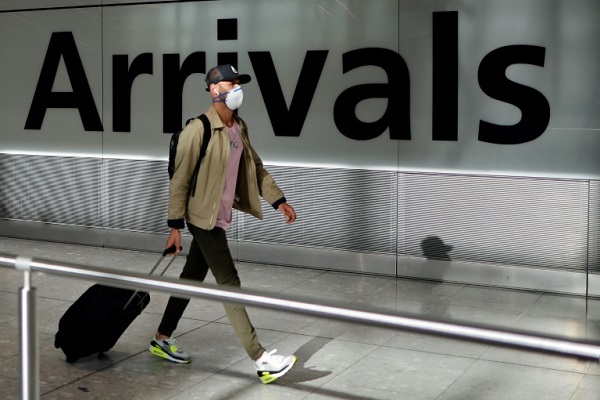 مسافر يضع كمامة أثناء وصوله إلى مطار هيثرو في شرق لندن
