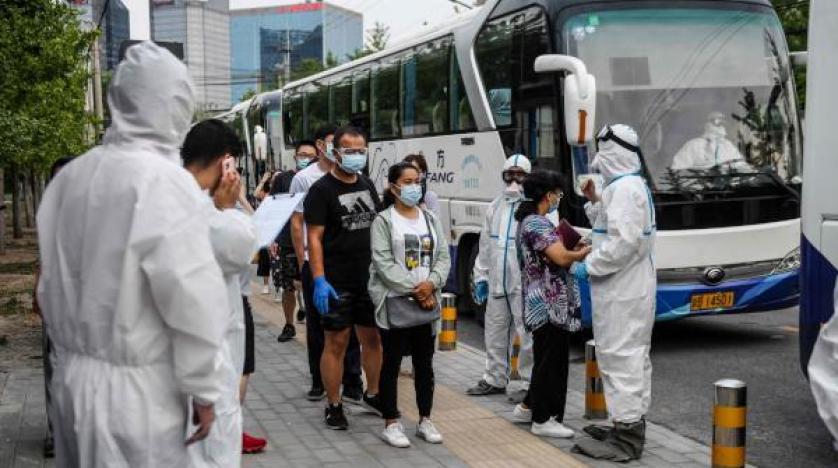 أشخاص ينتظرون إجراء اختبارات مسح لفيروس كورونا بعد نقلهم بالحافلات إلى مركز اختبار في بكين (ا.ف.ب)