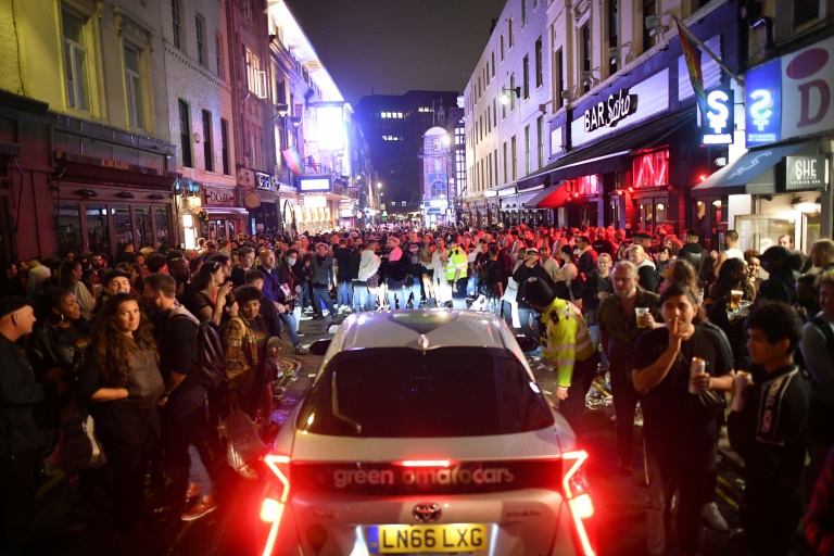 سيارة تحاول العبور بين الساهرين في أحد شوارع حي سوهو في لندن، 4 تموز/يوليو 2020