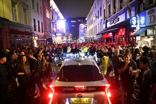 سيارة تحاول العبور بين الساهرين في أحد شوارع حي سوهو في لندن