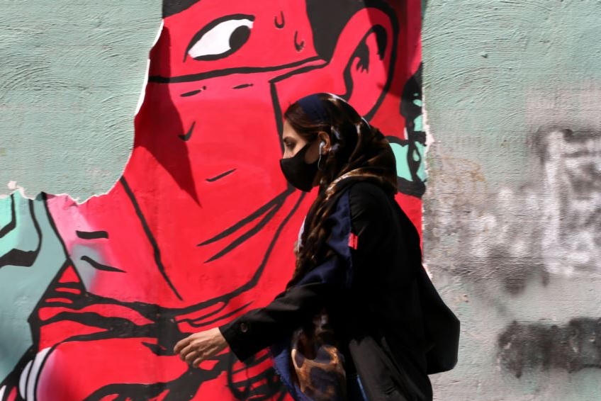 امرأة إيرانية تمر أمام رسم غرافيتي في طهران 