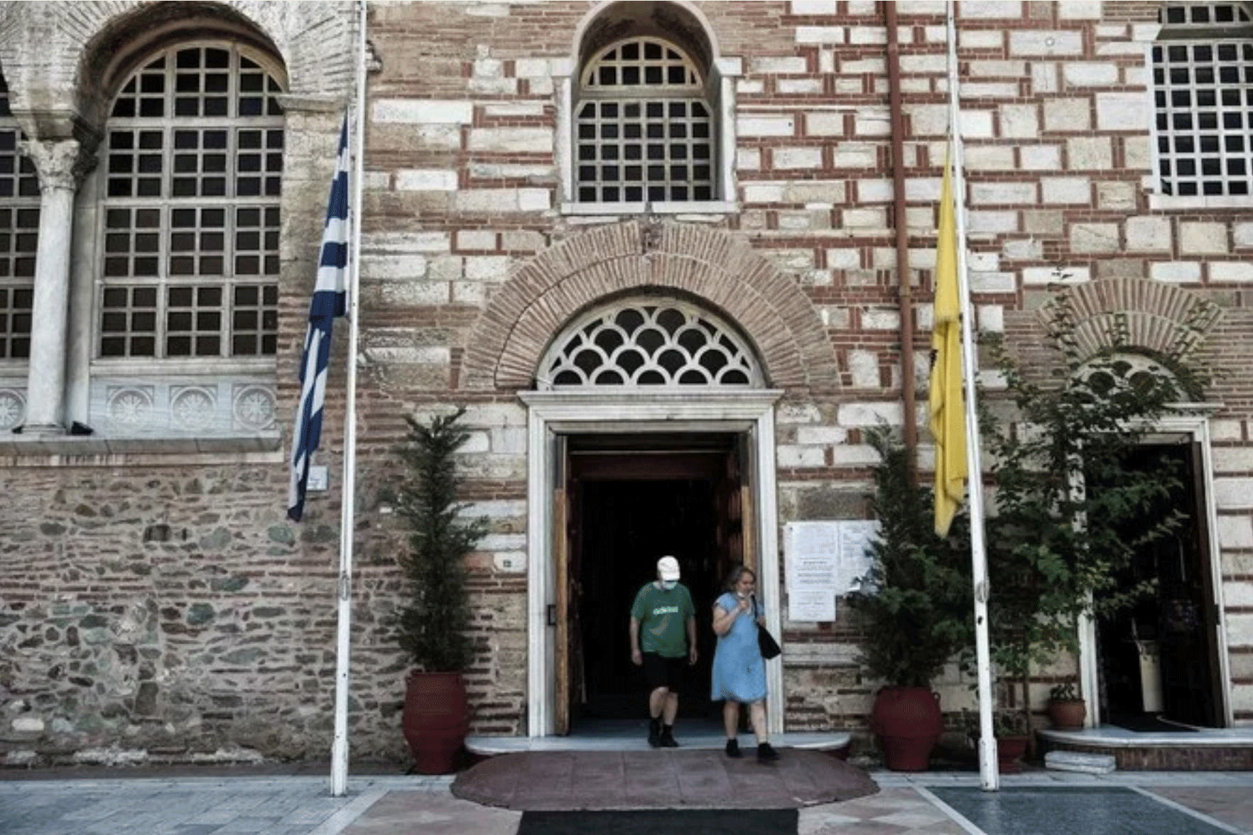مصليان يغادران كنيسة في تسالونيكي يوم 24 يوليو 2020، وتبدو الأعلام منكسة كفعل احتجاج على تحويل آيا صوفيا إلى مسجد 