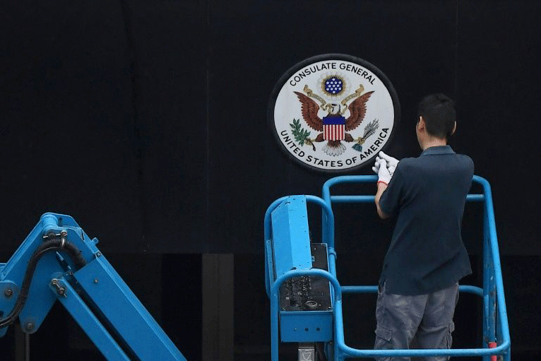 عامل يزيل شعار الولايات المتحدة من أمام القنصلية الأميركية في مدينة تشنغدو الصينية
