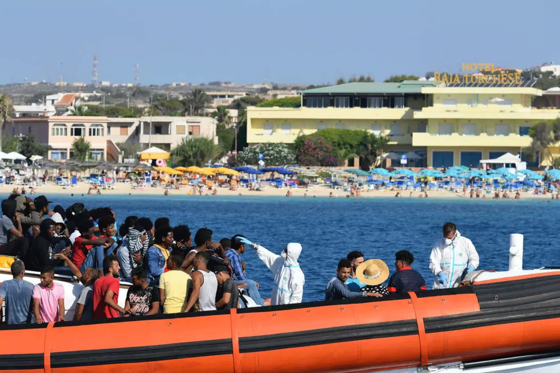 مهاجرون يخضعون للفحص الطبي على متن قاربهم لدى وصولهم إلى جزيرة لامبيدوسا الإيطالية في الأول من أغسطس 2020