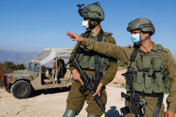 جنديان إسرائيليان يراقبان الحدود اللبنانية من موقعهما في بلدة المطلة