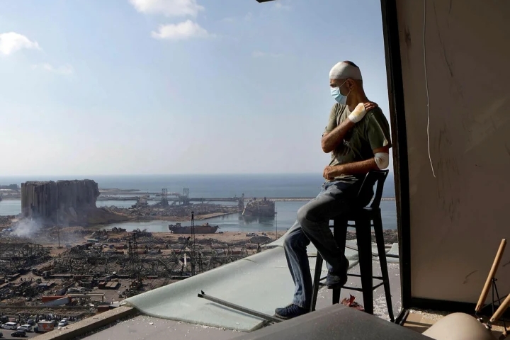 جريح يتأمل الدمار الذي خلفه انفجار بيروت من شرفة مطلة على المرفأ
