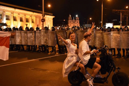 يمران خلال تظاهرة أمام شرطة مكافحة الشغب في مينسك مساء الأحد 9 أغسطس 2020