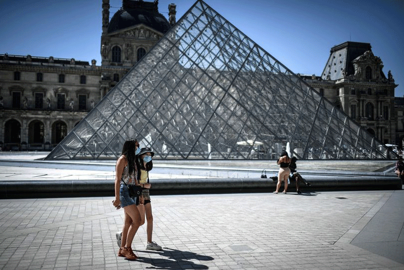 مارة أمام متحف اللوفر، أيقونة السياحة في باريس