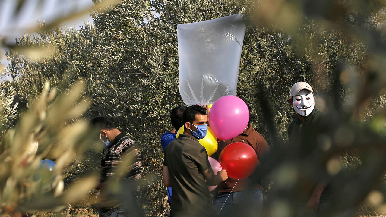 فلسطينيون ملثمون يجهزون بالونات حارقة بالقرب من مخيم البريج للاجئين الفلسطينيين على طول الحدود مع إسرائيل في 12 اغسطس 2020
