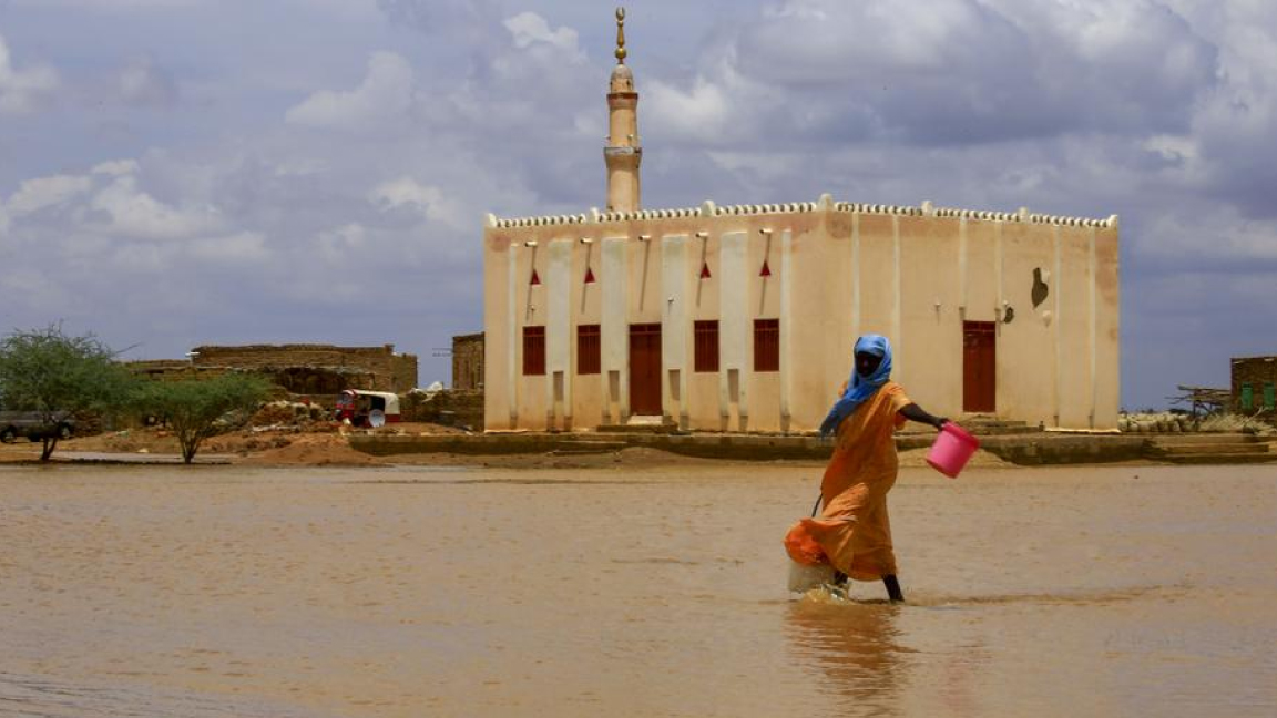 سودانية تغادر منزلها الذي غمرته السيول في 6 أغسطس الجاري