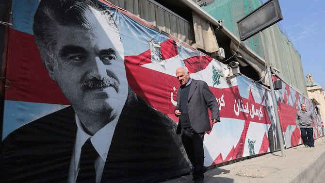 رجل يسير بالقرب من صورة عملاقة للرئيس الأسبق رفيق الحريري في ذكرى اغتياله التاسعة في 14 فبراير 2014