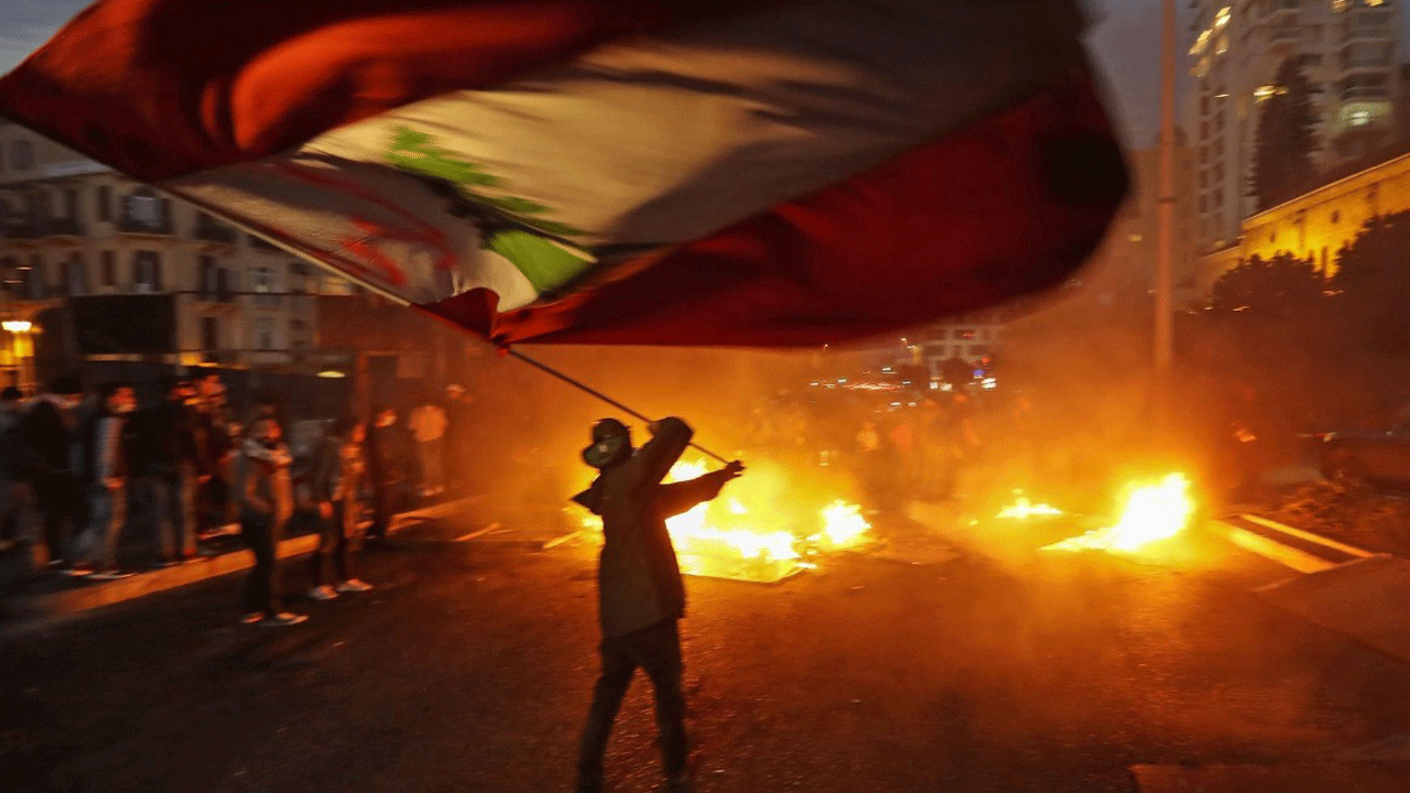 علم لبنان مرفوعاً من متظاهر في بيروت رفضاً للسلاح غير الشرعي والفساد