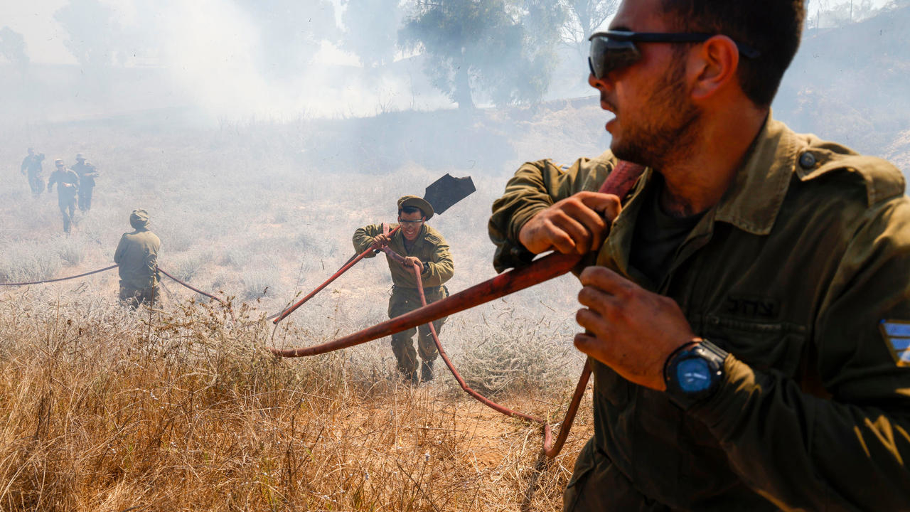 عسكريون إسرائيليون بحاولون إطفاء حريق اندلع في حقل في جنوب إسرائيل قرب الحدود مع قطاع غزة في 23 اغسطس 2020 