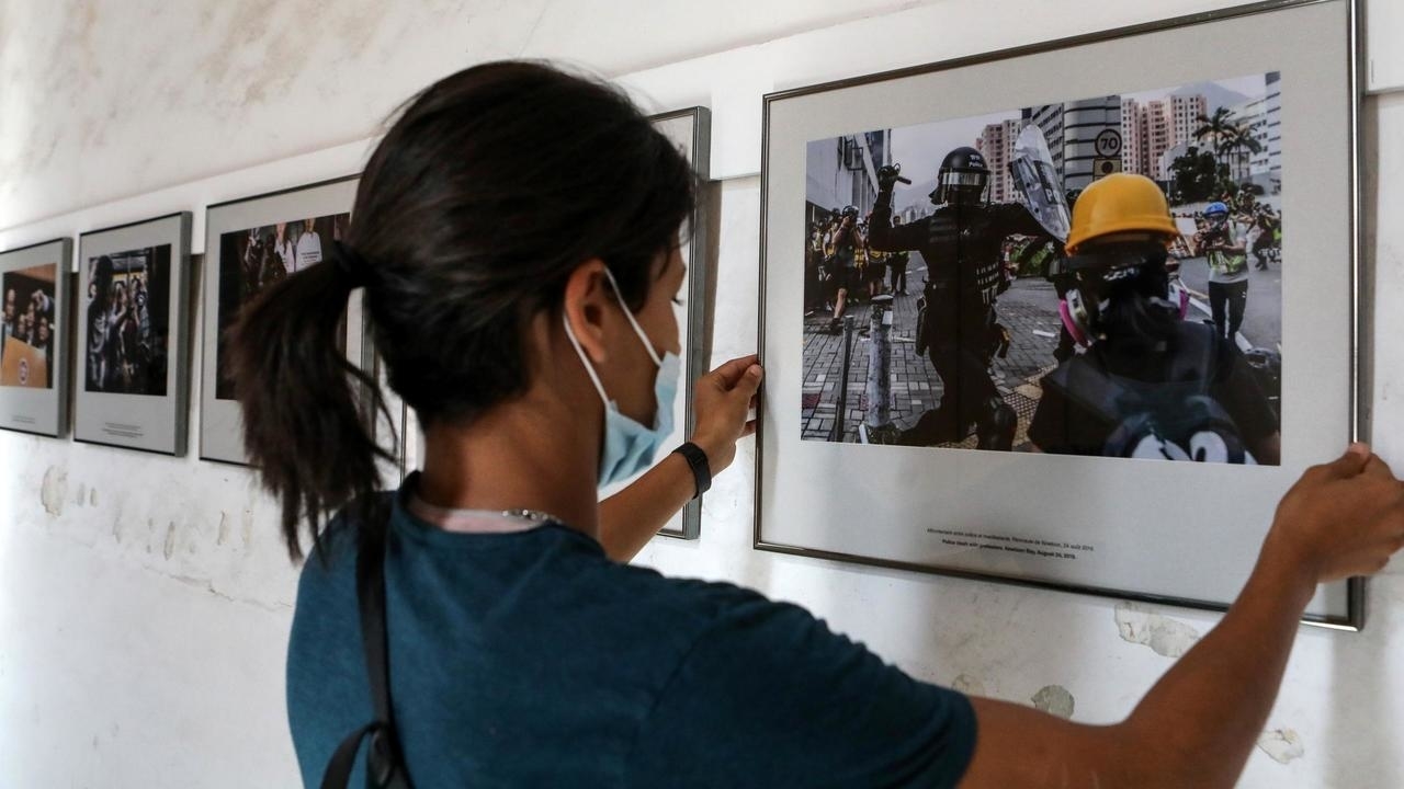موظفة تعلق صورا من احتجاجات هونغ كونغ في إطار معرض في جنوب فرنسا في 25 أغسطس 2020