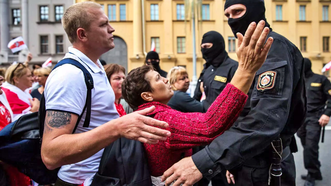 تتحدث مع رجل أمن في أثناء مظاهرات حاشدة للمطالبة برحيل الرئيس ألكسندر لوكاشينكو