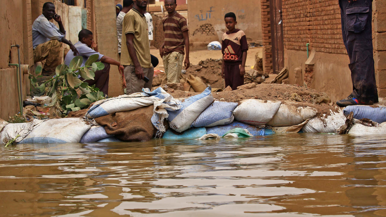 سودانيون يقفون وسط مياه فاضت من نهر النيل في جزيرة توتي الى جانب أكياس من الرمال يستخدمونها في محاولة لوقف المياه في الثالث من سبتمبر 2020