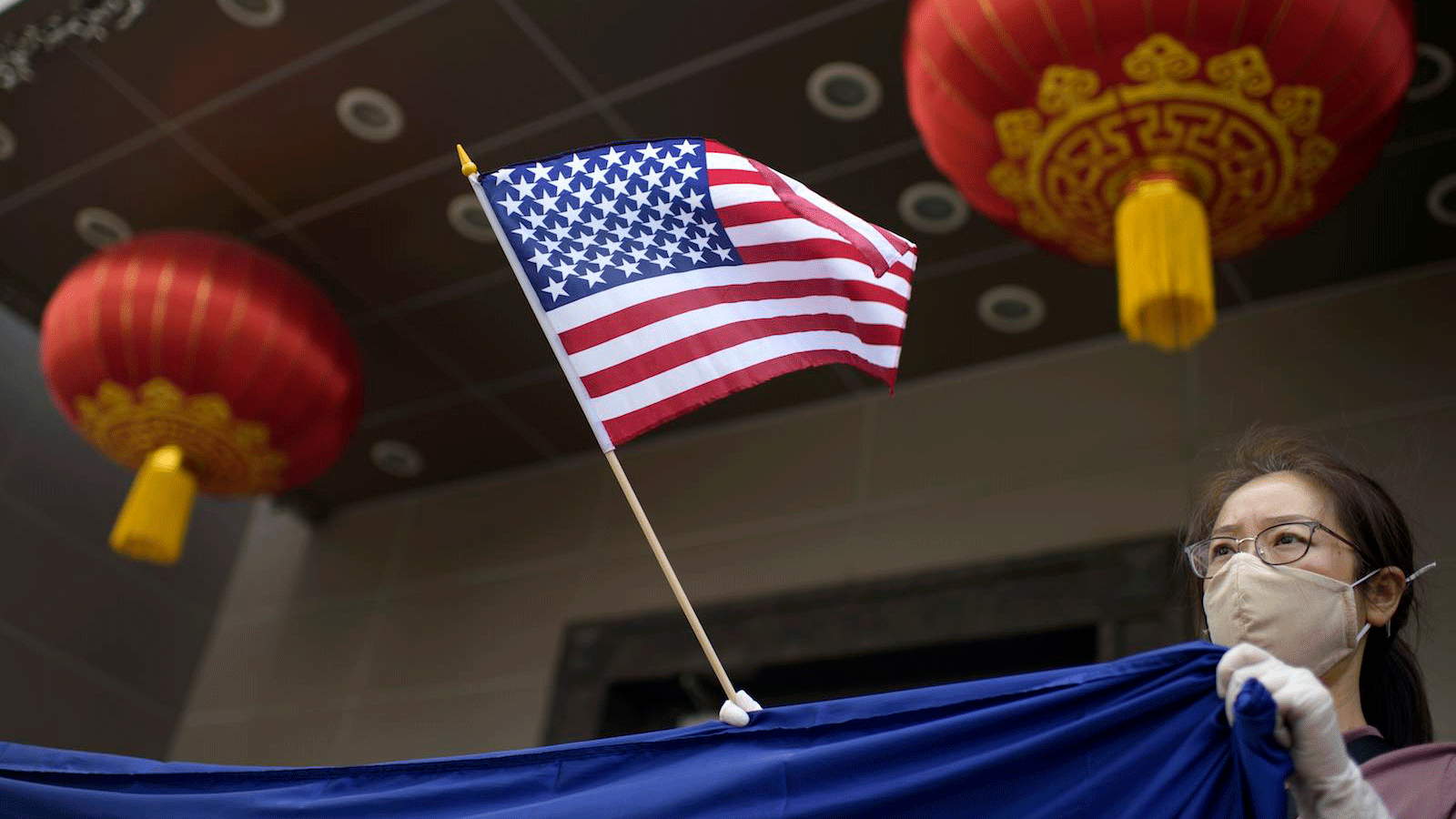 متظاهرة صينية ترفع العلم الأميركي أمام القنصلية الصينية في هيوستن والتي أمر ترمب بإغلاقها