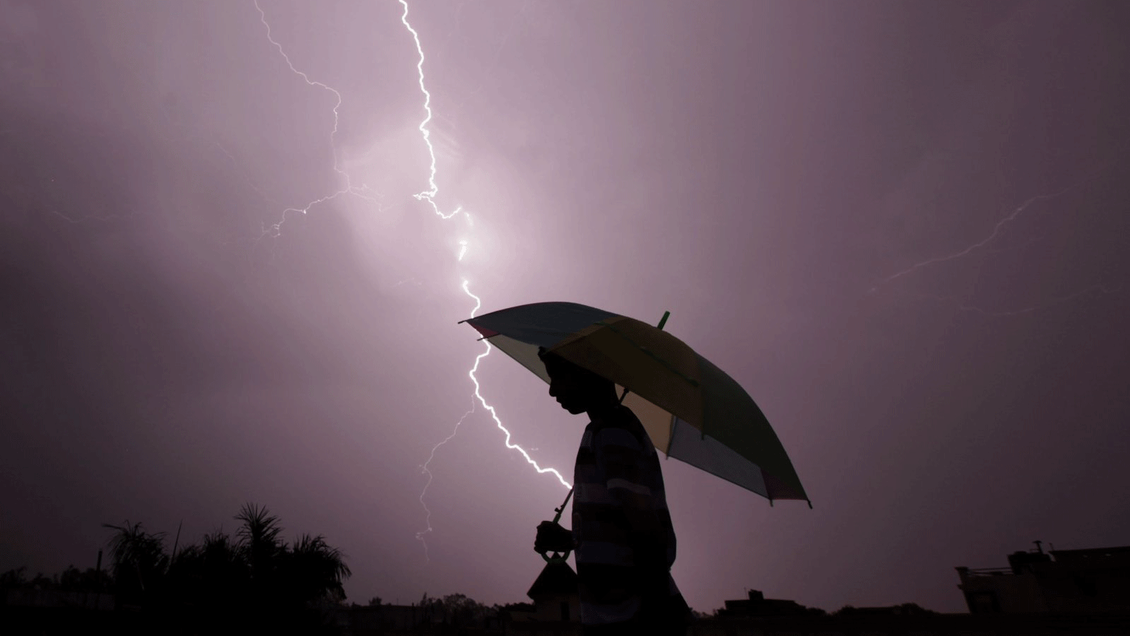 أحد المارة يسير حاملاً مظلة في ليلة عاصفة جامو، الهند، في 15 مايو 2015
