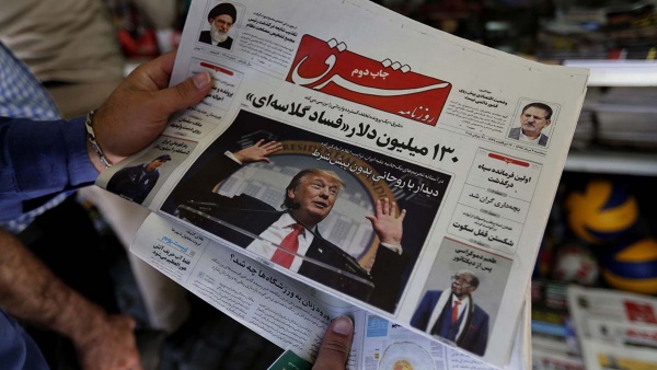 رجل يقرأ في طهران صحيفة يتصدر الرئيس الأميركي صدر صفحتها الأولى