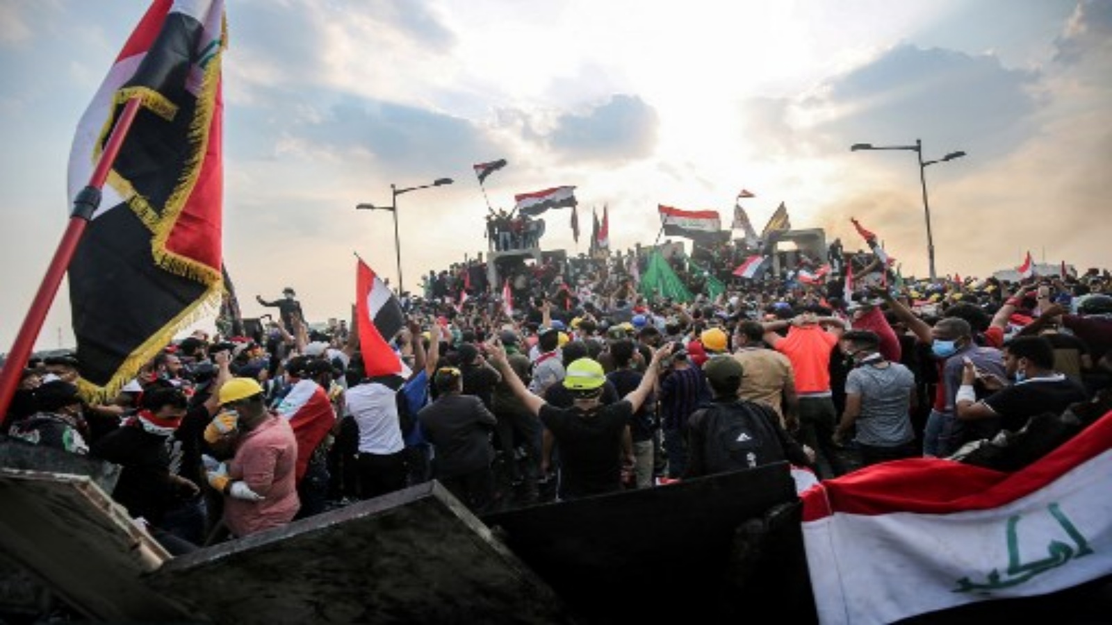 هذه الصورة التي التقطت في 29 أكتوبر / تشرين الأول 2019 ، المتظاهرون العراقيون يلوحون بالأعلام الوطنية وهم يقفون فوق حواجز خرسانية عبر جسر الجمهورية في العاصمة بغداد الذي يربط بين ساحة التحرير والمنطقة الخضراء شديدة الحراسة. أ ف ب