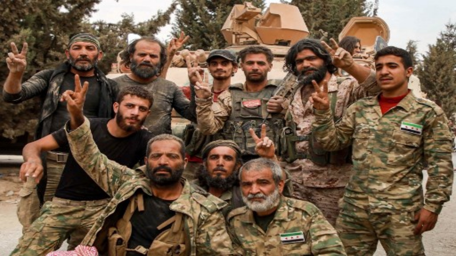 مقاتلون سوريون مدعومون من تركيا ، مع أحدهم (الثالث من اليمين في الأعلى) يرتدي شعار حركة 
