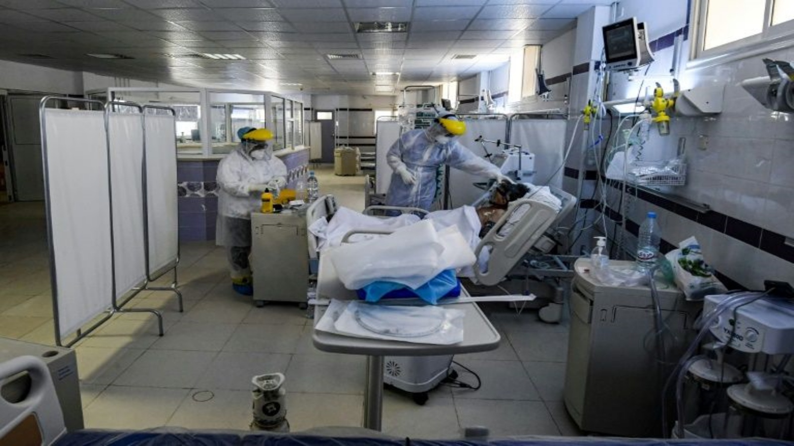 ممرضات يرتدون معدات الوقاية الشخصية للعناية بمريض Covid-19 تحت أنبوب في وحدة العناية المركزة في مستشفى في مدينة قابس في جنوب غرب تونس. أ ف ب