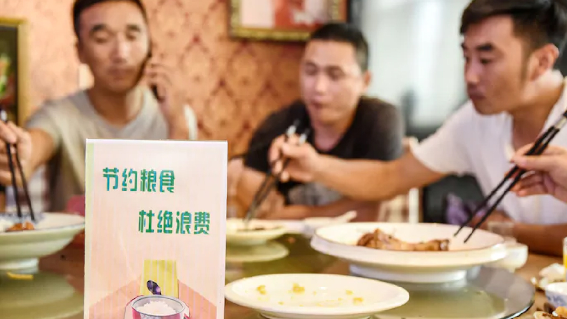 إعلان تنبيهي على مائدة في مطعم صيني يدعو إلى وقف هدر الطعام