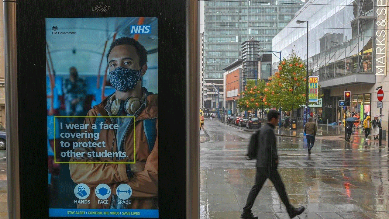 رجل يمر من أمام لافتة الكترونية تدعو لوضع الكمامات في مانشستر بتاريخ 6 تشرين الاول/أكتوبر 2020