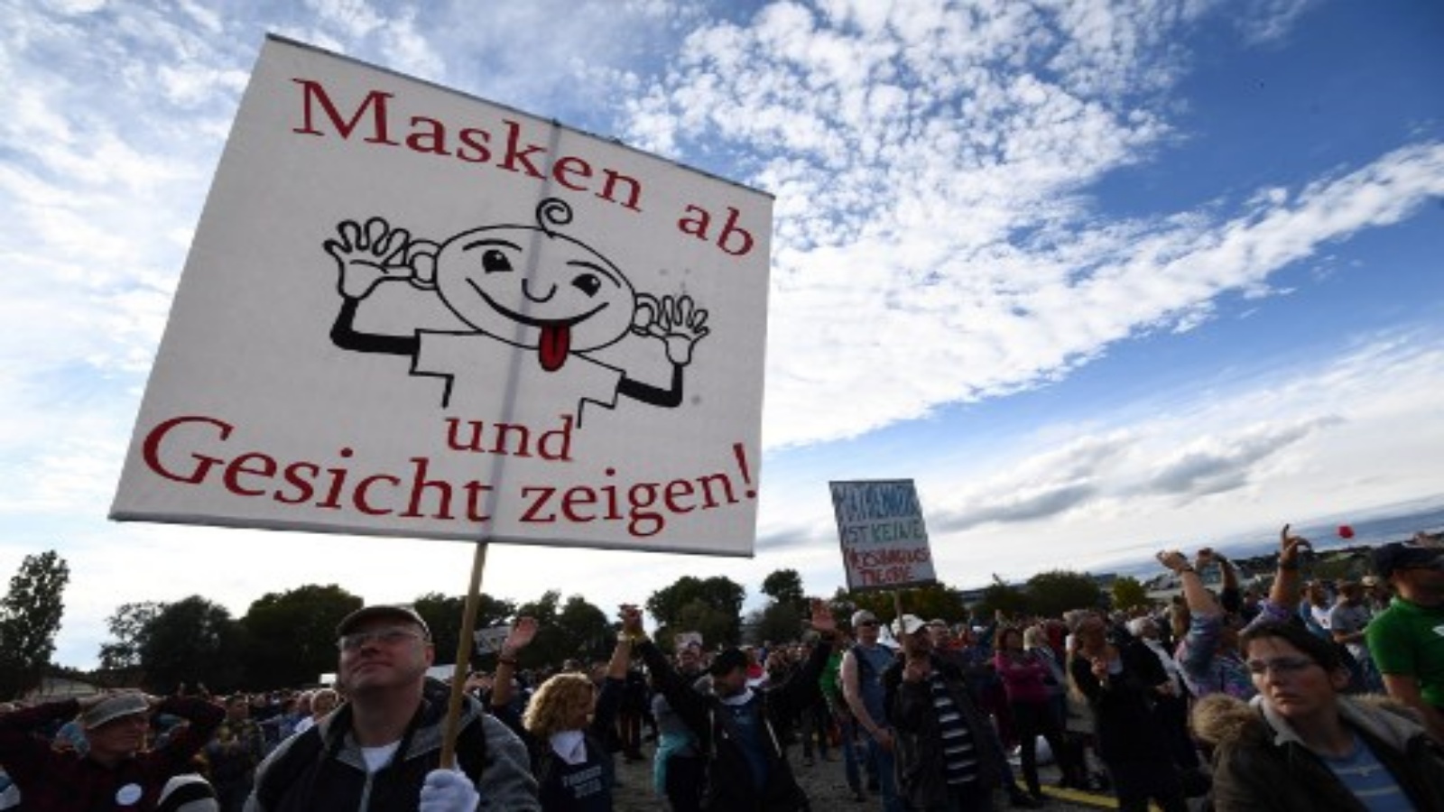 متظاهرون يحملون لافتة كتب عليها `` انزع القناع واظهر وجهك '' أثناء مشاركتهم في احتجاج ضد الأقنعة والقيود المفروضة على الفيروسات خلال جائحة فيروس كورونا الجديد Covid-19 المستمر في كونستانس جنوب ألمانيا في 4 أكتوبر 2020