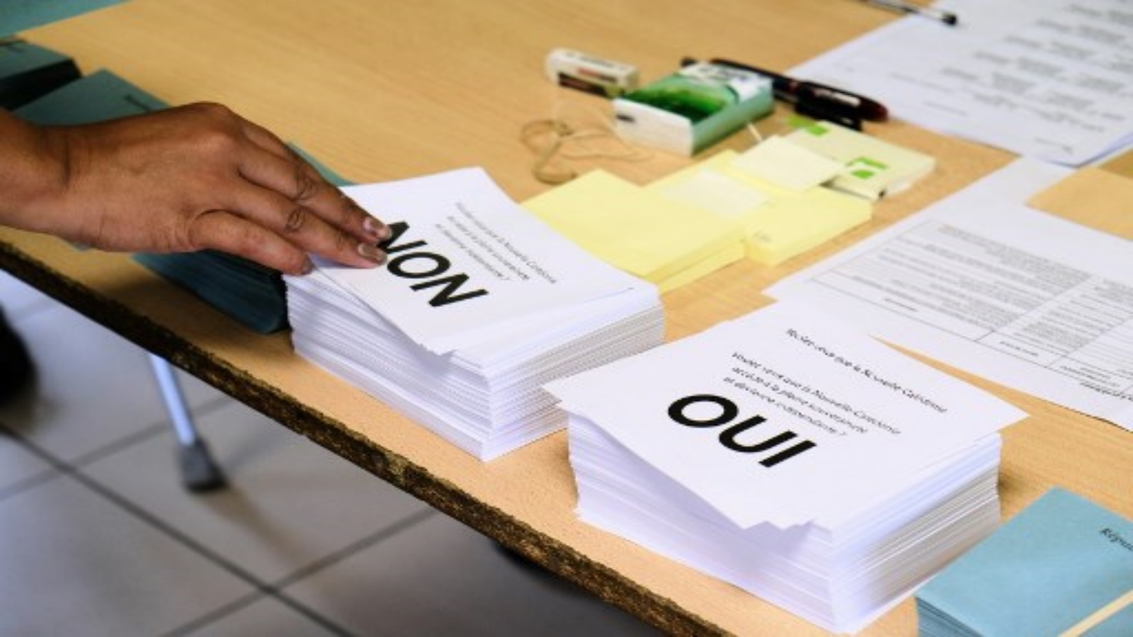 شخص يختار استمارة التصويت بينما يستعد للإدلاء بصوته في مركز اقتراع في الاستفتاء على الاستقلال في إقليم جنوب المحيط الهادئ الفرنسي في كاليدونيا الجديدة في نوميا في 4 أكتوبر 2020