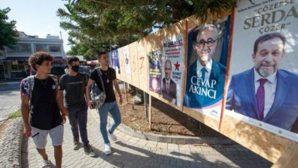 قبارصة أتراك يمرون أمام ملصقات انتخابية الجمعة