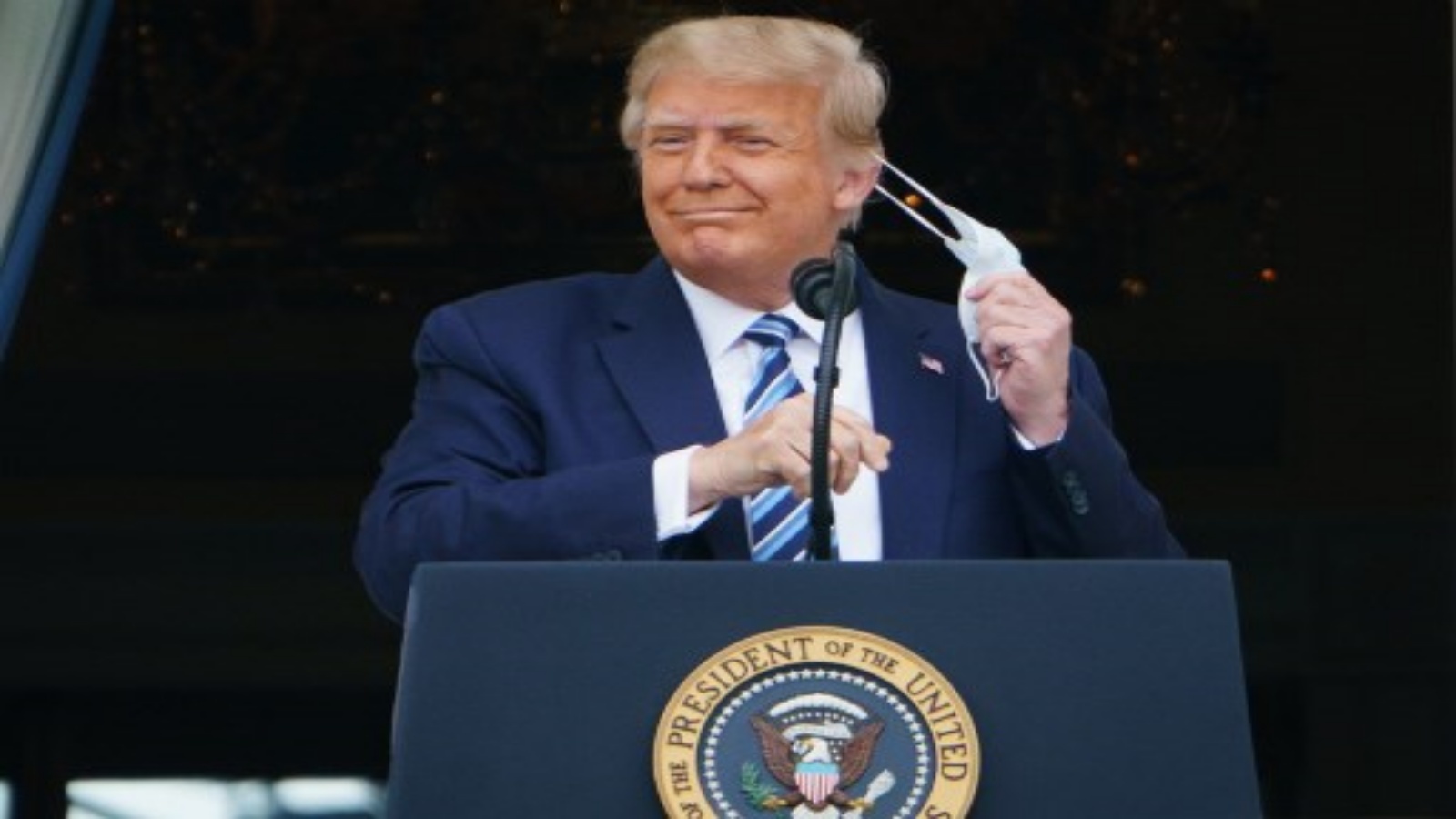 الرئيس الأمريكي دونالد ترمب يخلع قناعه قبل أن يتحدث من جنوب الرواق بالبيت الأبيض في واشنطن العاصمة خلال تجمع حاشد في 10 أكتوبر 2020