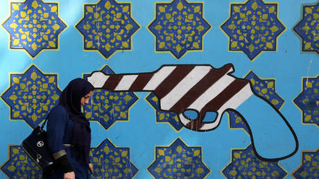 امرأة تسير أمام لوحة جدارية في طهران