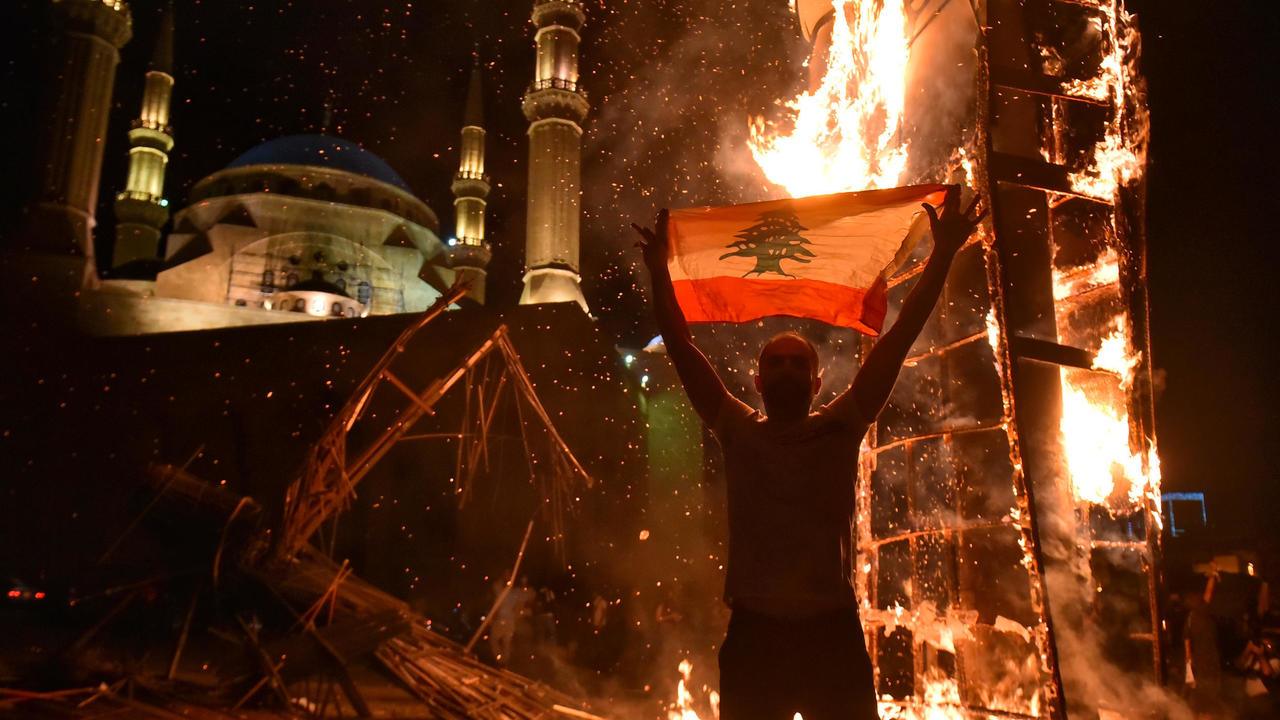 متظاهر يرفع العلم اللبناني قبالة مجسّم 