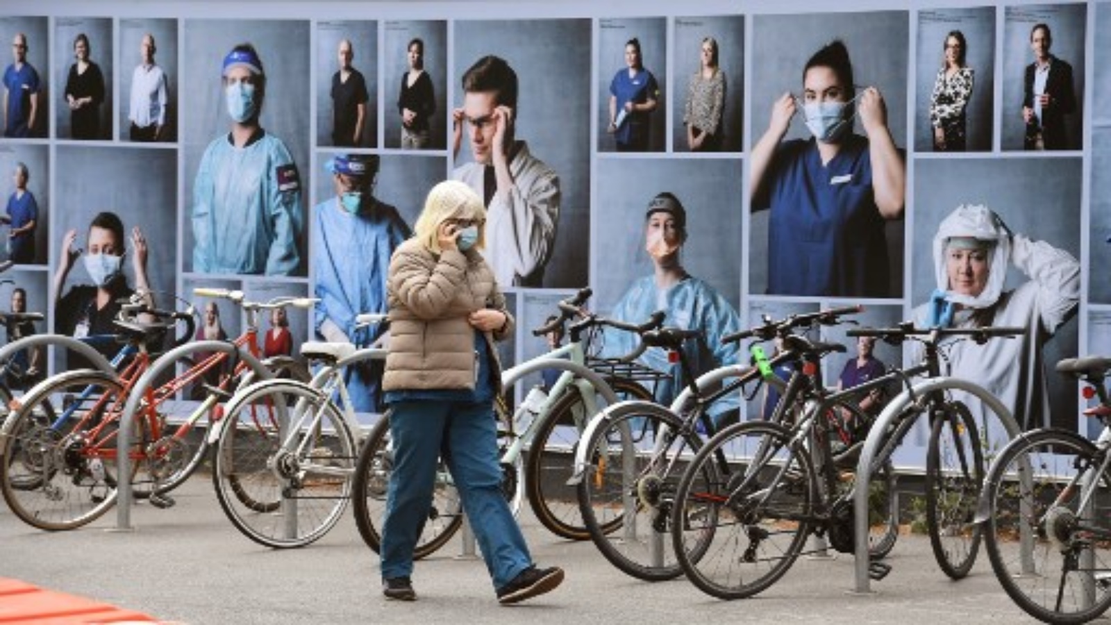 امرأة تمر أمام عرض للصور خارج مستشفى ملبورن الملكي في 20 أكتوبر 2020 ، لشكر العاملين في مجال الرعاية الصحية حيث تسجل ولاية فيكتوريا حالة إصابة جديدة بفيروس كورونا COVID-19.