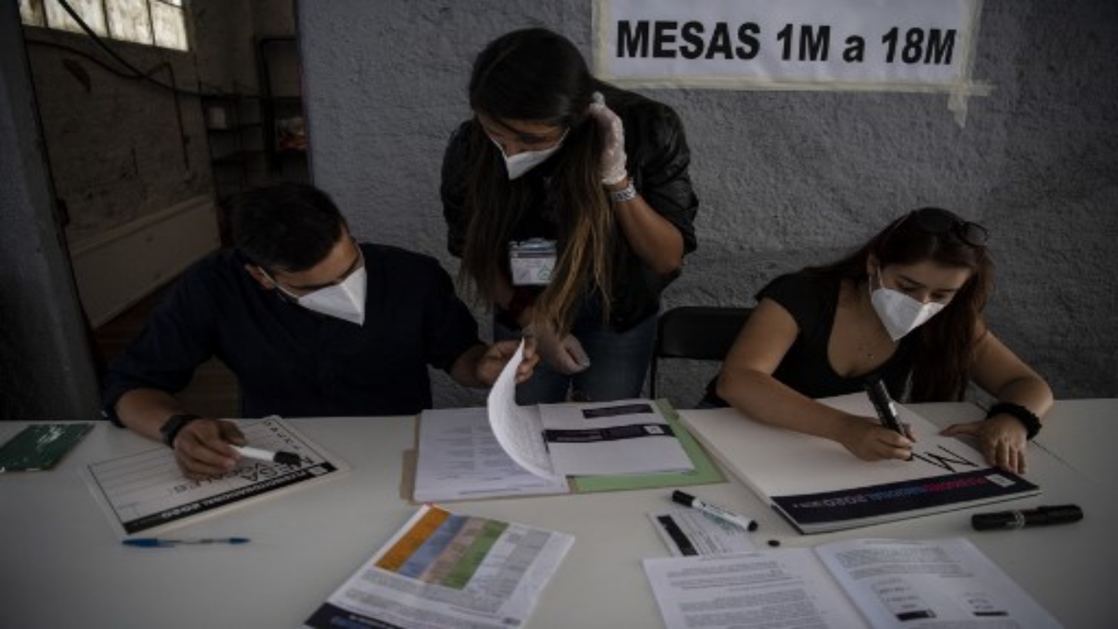 عمال الخدمة الانتخابية في تشيلي (سيرفيل) مركز اقتراع عشية التصويت على الاستفتاء الدستوري على مستوى البلاد في سانتياغو في 24 أكتوبر 2020