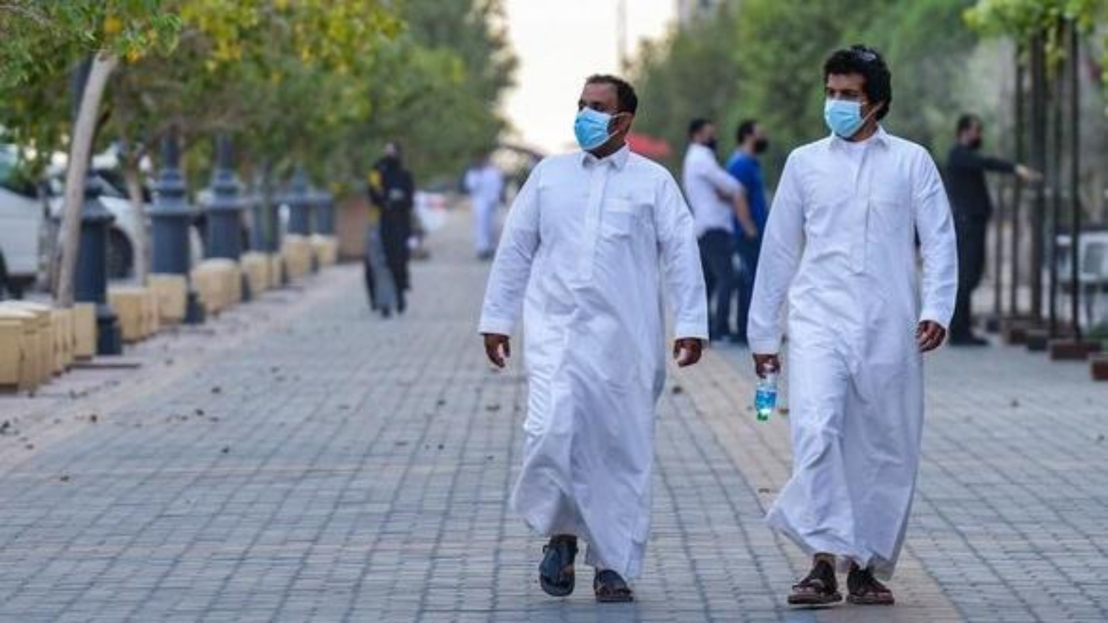  شابان ملتزمان بالإجراءات الصحية في أحد شوارع الرياض