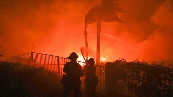 رجال الإطفاء يحاولون إخماد النيران من فناء المنزل في ولاية كاليفورنيا