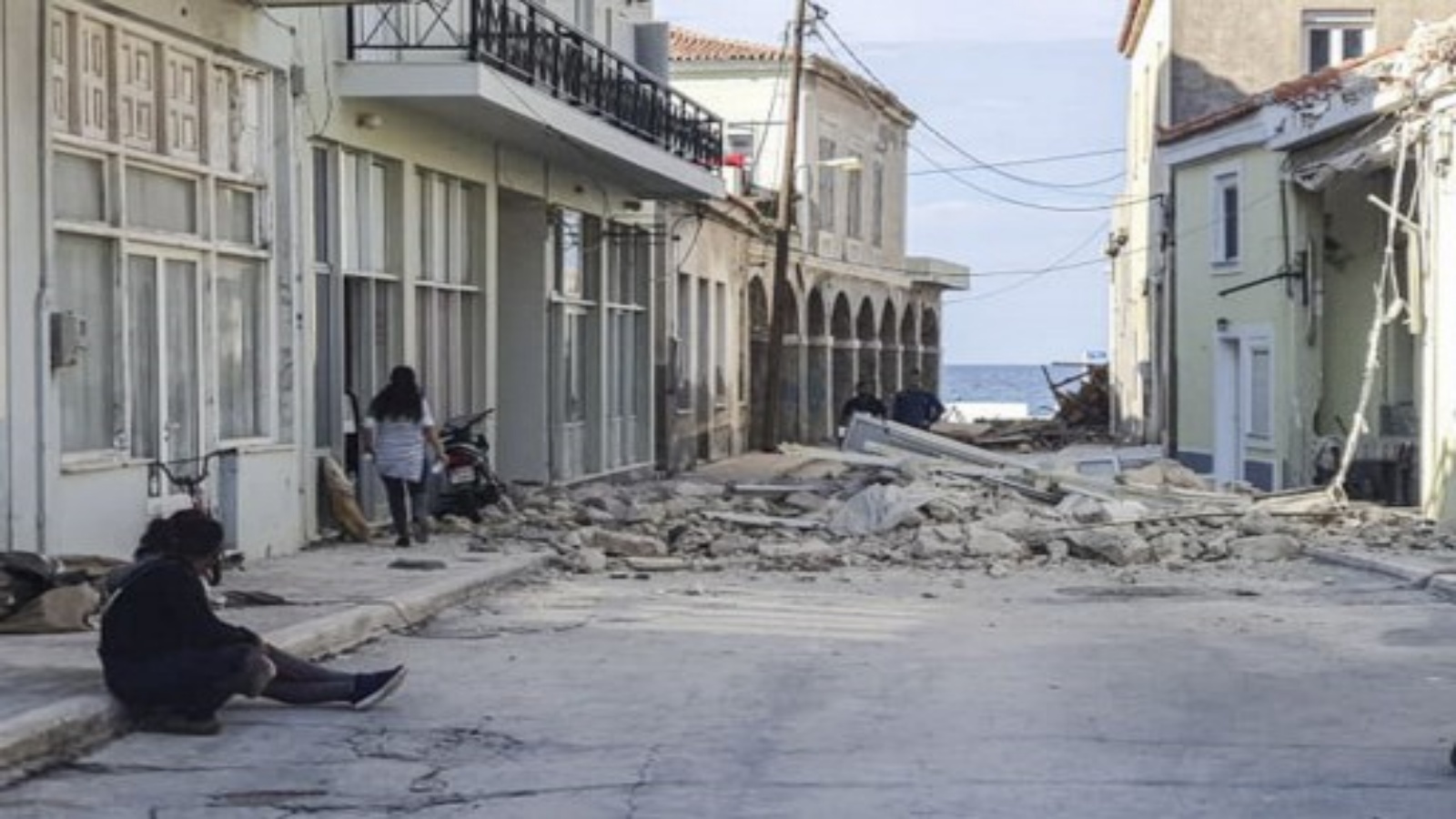 أشخاص يمشون أمام منزل مدمر بعد زلزال ضرب جزيرة ساموس في 30 أكتوبر 2020. ضرب زلزال قوي اليونان وتركيا في 30 أكتوبر 2020 
