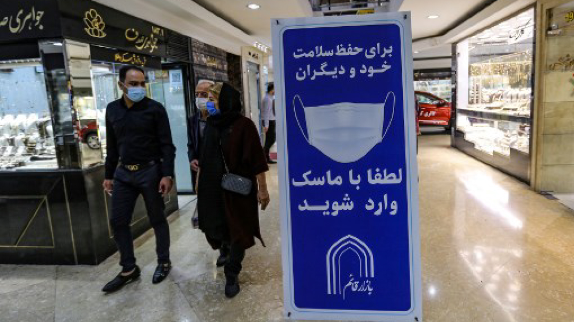 إيرانيون يمرون الجمعة أمام إعلان توعوي بأهمية الكمامة في أحد متاجر طهران