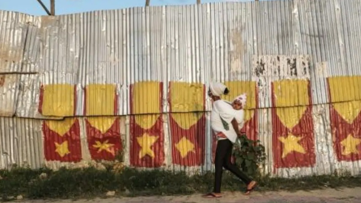 امرأة ووليدها تمر بجدار رسم عليه علم التيغراي بشمال إثيوبيا في سبتمبر الماضي