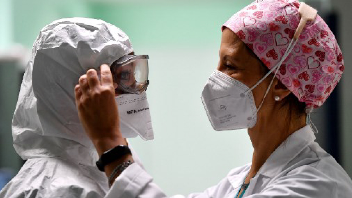 ممرضة تضبط قناع زميلتها في أحد مستشفيات إيطاليا