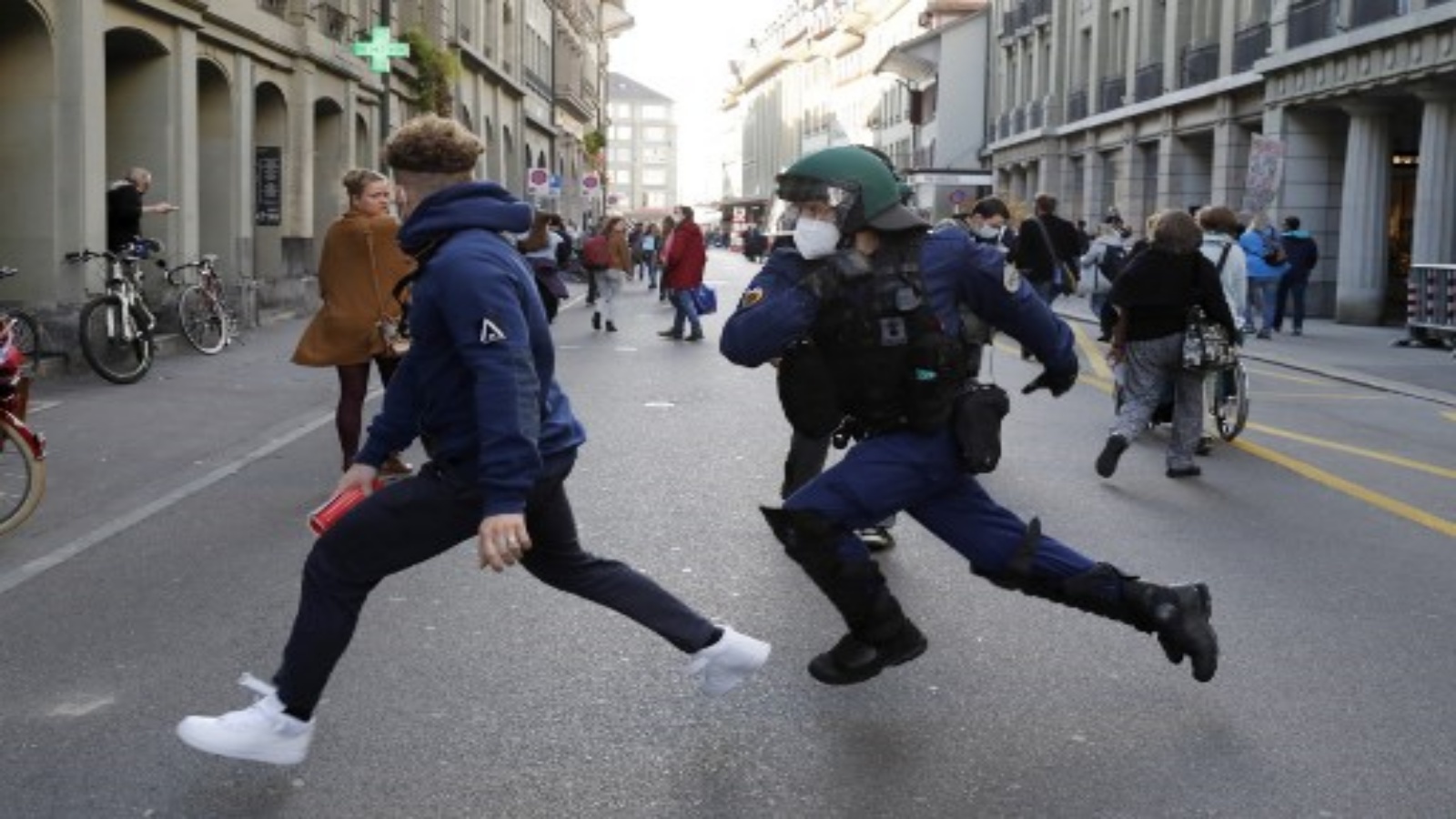 ضابط شرطة يطارد متظاهرًا خلال مظاهرة في برن في 31 أكتوبر 2020 ، احتجاجًا على الإجراءات الجديدة التي اتخذتها السلطات السويسرية لكبح حالات الإصابة بفيروس كورونا في البلاد.