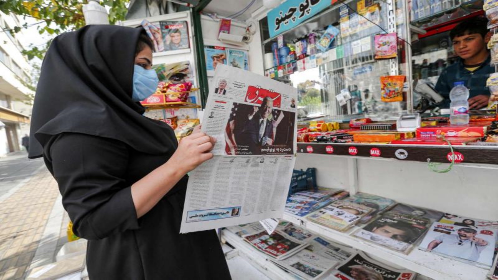 امرأة إيرانية تتصفح نسخة من صحيفة فارسية تعرض نتائج الانتخابات العامة الأمريكية لعام 2020 في كشك إخباري في العاصمة الإيرانية طهران في 8 نوفمبر