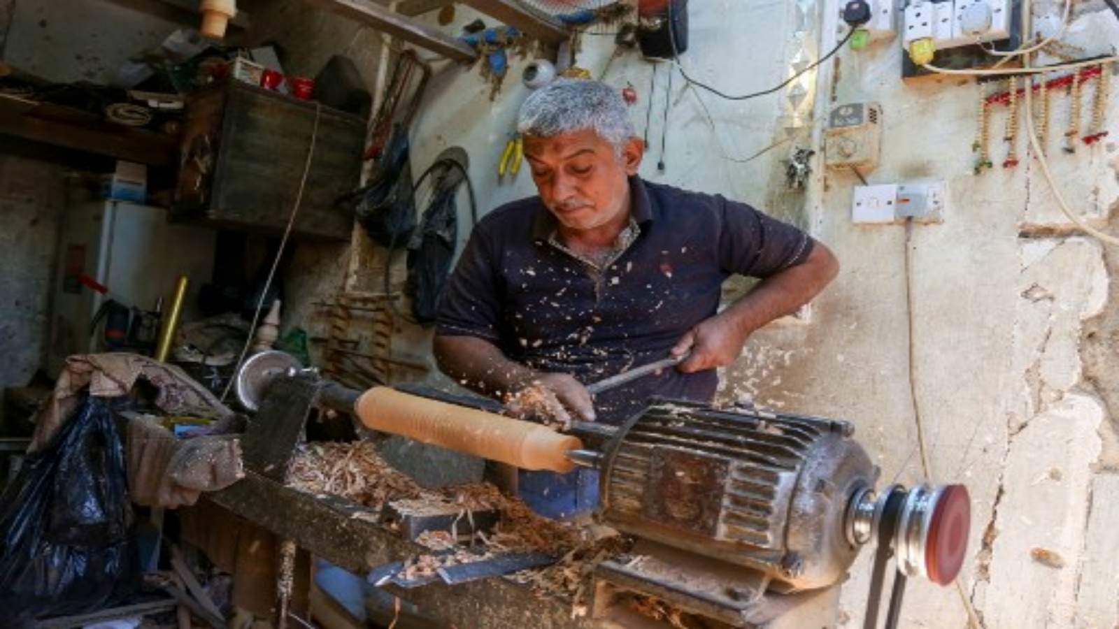 نجار يعالج قطعة من الخشب لصنع النرجيلة في ورشته في مدينة كربلاء المقدسة وسط العراق في 21 أكتوبر 2020.