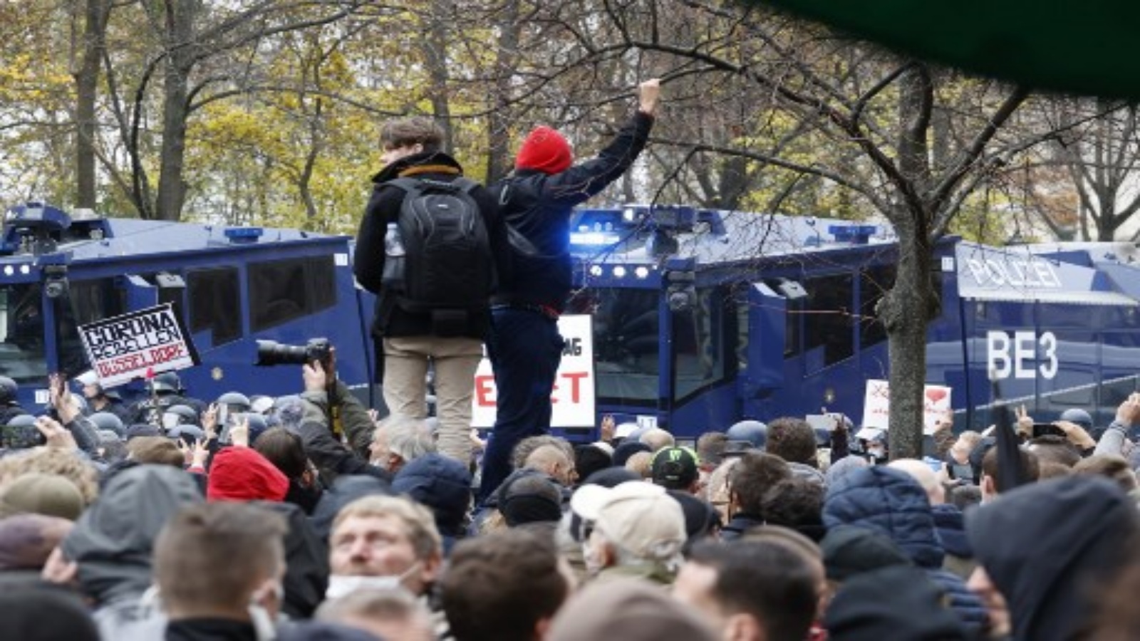 متظاهرون يقفون بجوار سيارات الشرطة المدرعة خلال احتجاج على الإجراءات التي فرضتها الحكومة الألمانية للحد من انتشار فيروس كورونا الجديد ، في 18 نوفمبر 2020 بالقرب من بوابة براندنبورغ في برلين