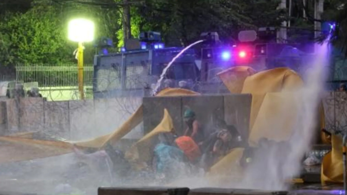 متظاهرون مطالبون بتعزيز الديموقراطية يحتمون من خراطيم مياه الشرطة في بانكوك الثلاثاء