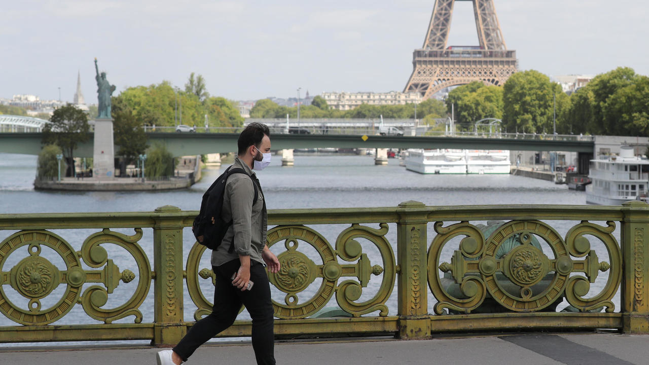 رجل يعبر جسر ميرابو قرب برج ايفل ونسخة تمثال الحرية في باريس في 27 آب/أغسطس 2020
