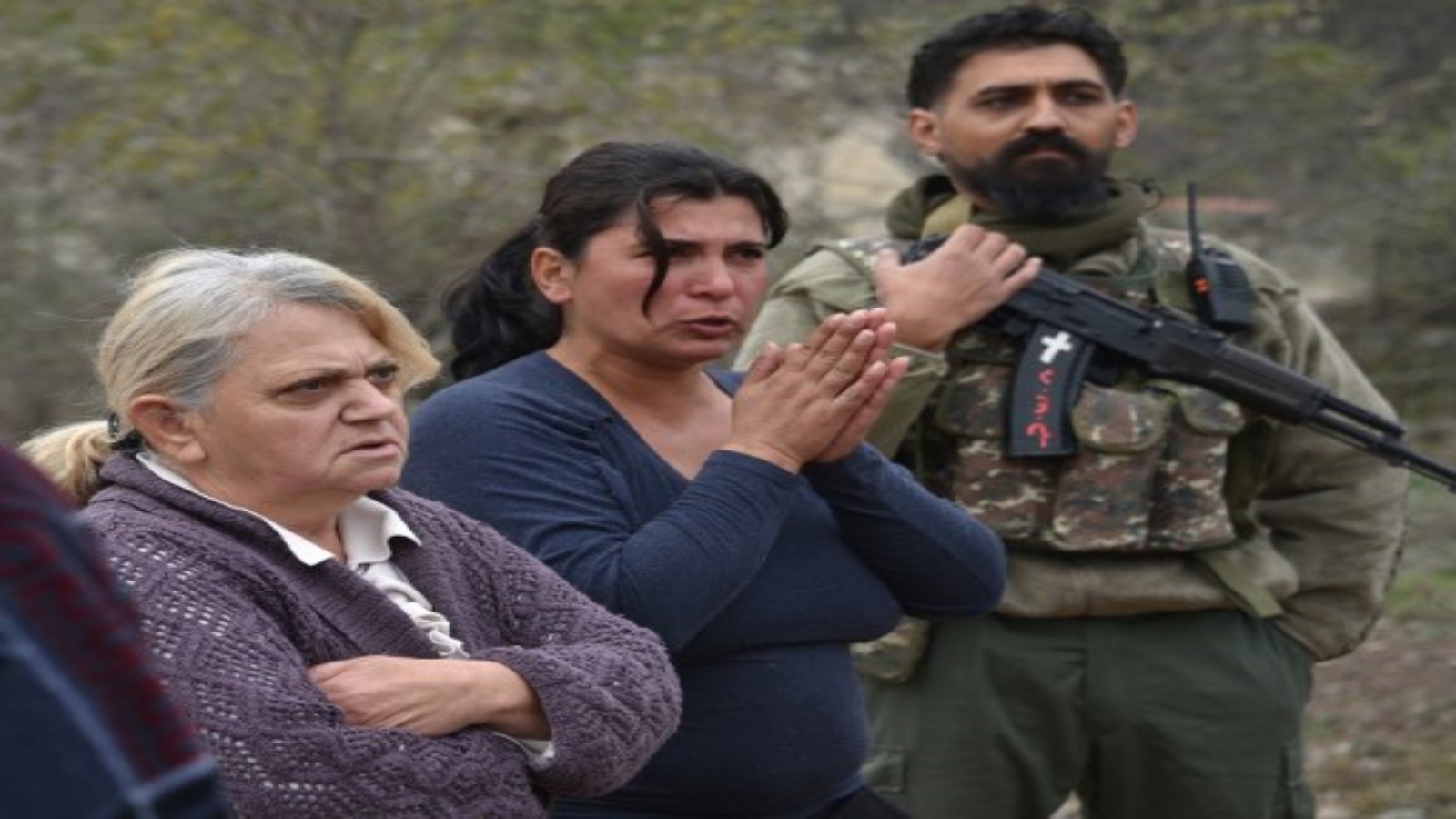 نساء يقفن بجانب قروي متطوع يرتدي زي الجيش المموه ويحملن بندقية كلاشينكوف في دورية في قرية زابوكس بالقرب من ممر لاتشين في 26 نوفمبر 2020 ، بعد ستة أسابيع من القتال بين أرمينيا وأذربيجان حول منطقة ناغورنو كاراباخ المتنازع عليها